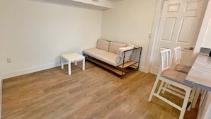 Una habitación pequeña y poco amueblada, con un sofá, una mesita y una silla.