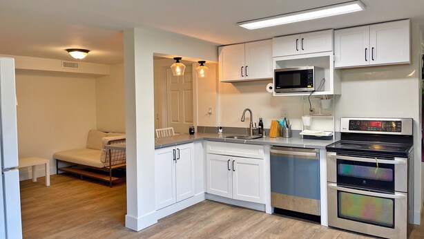 Una cocina moderna con armarios blancos, electrodomésticos de acero inoxidable y suelo de madera.