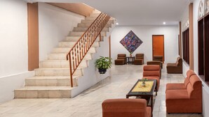 A spacious lobby with a marble staircase, comfortable seating, and a large decorative wall piece.