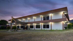 A modern building with a flat roof, multiple windows, and a covered entrance area.