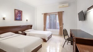 A hotel room with two beds, a desk, a chair, a TV, and a window with curtains.