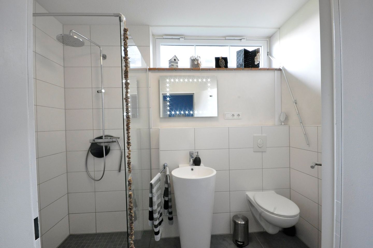 A modern bathroom with a shower, toilet, and sink.