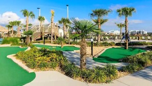 Ein Golfplatz mit Palmen, ein Gebäude im Hintergrund und ein klarer, blauer Himmel.