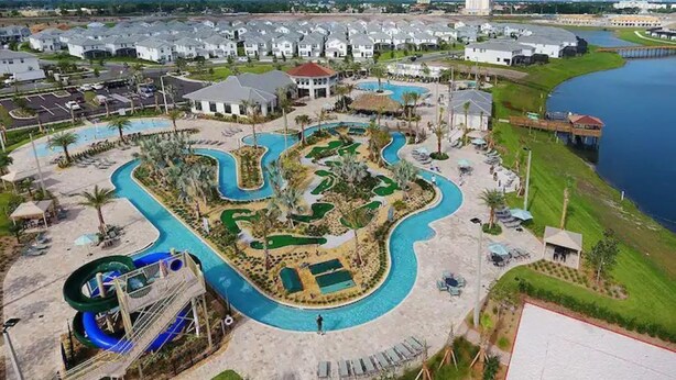 Ein Luftbild eines Resorts mit mehreren Schwimmbecken, einer Wasserrutsche und einer weitläufigen Strandpromenade.
