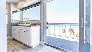 Eine moderne Küche mit weißen Schränken und Granit-Arbeitsplatten, einem großen Fenster und einem Balkon mit Blick auf den Strand.