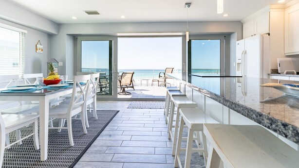 Eine moderne Küche mit weißen Schränken, einer Arbeitsplatte aus Granit und Blick aufs Meer.