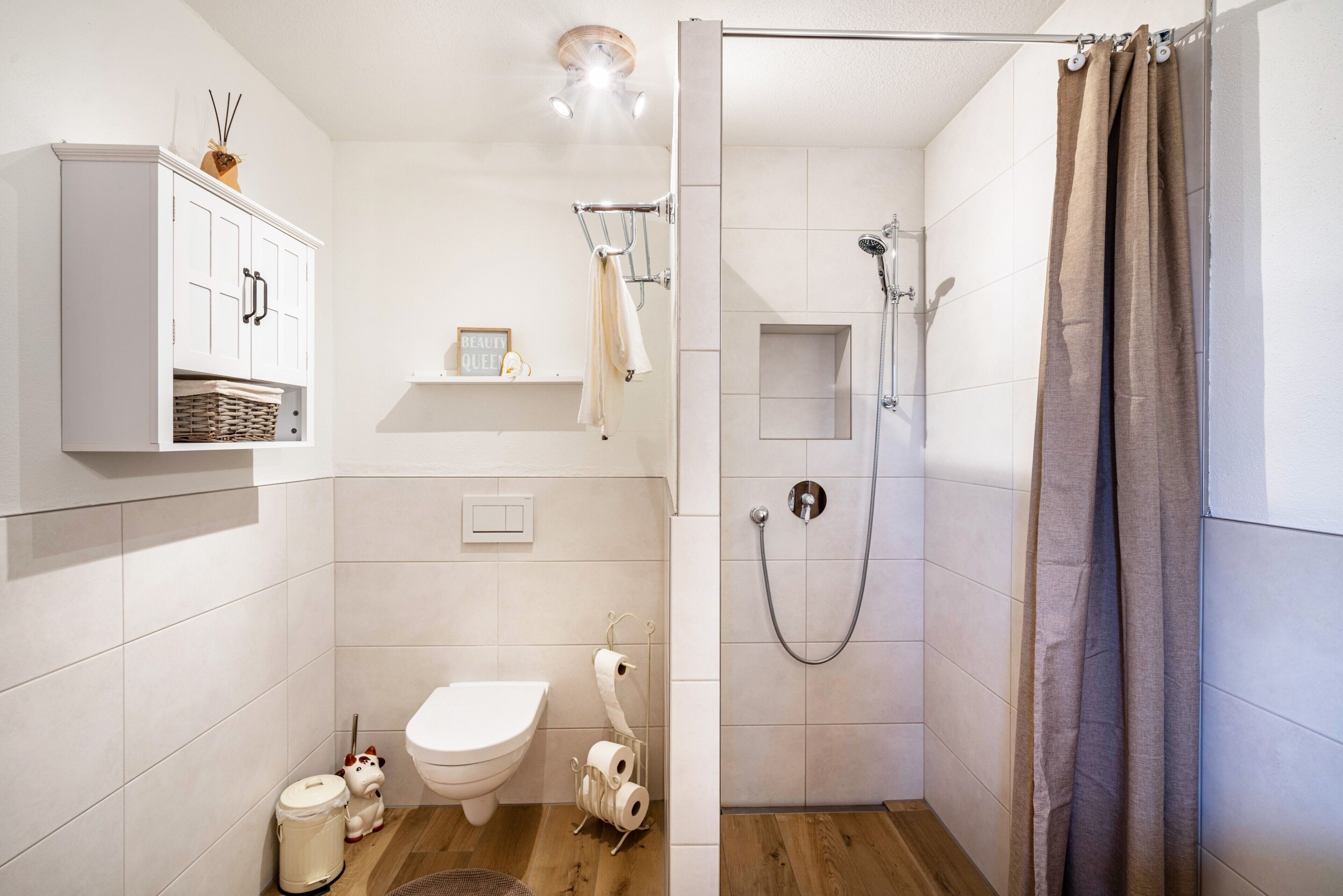 A small bathroom with a toilet, shower, and cabinet.