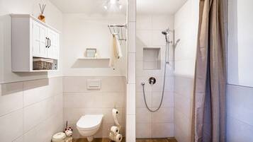 A small bathroom with a toilet, shower, and cabinet.