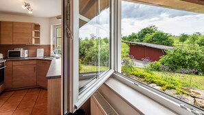 Eine Küche mit Holzausstattung, einer Mikrowelle und einem Fenster mit Blick auf einen Garten.