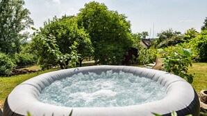 Ein aufblasbarer Whirlpool in einem Garten mit Bäumen und einem Schuppen im Hintergrund.