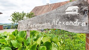 Ein hölzernes Schild mit dem Namen 'Jerrenwien Alexandra' in weißen Buchstaben.