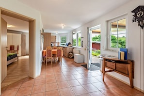A spacious kitchen with a dining area, a small refrigerator, and a wooden table with a clock.