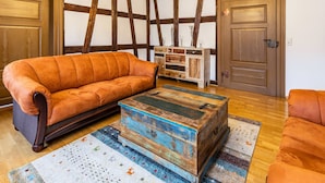 Una habitación con piso de madera, un sofá, un aparador y una puerta.