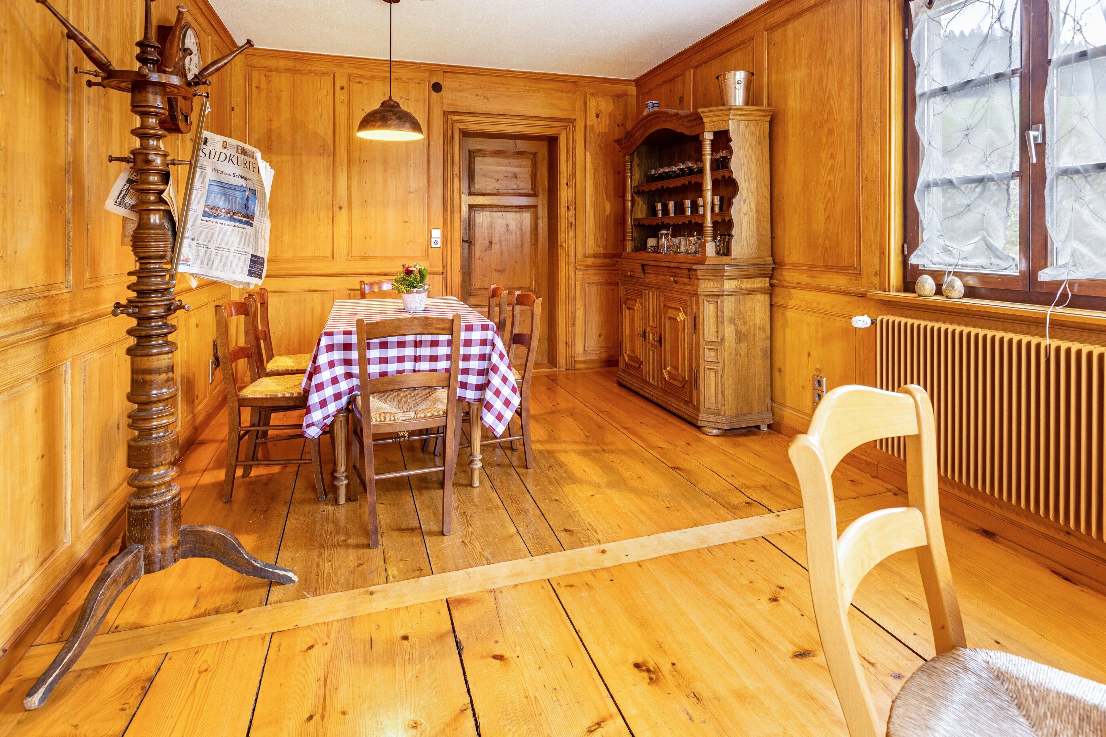 Un interior de madera con una mesa de comedor, sillas, un armario de madera y un radiador.