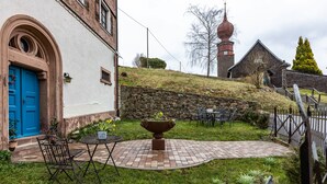 Un patio con muro de piedra, una puerta azul y una maceta grande.