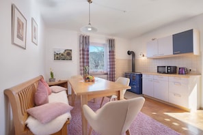 A cozy kitchen with a dining table, chairs, a microwave, and cabinets.