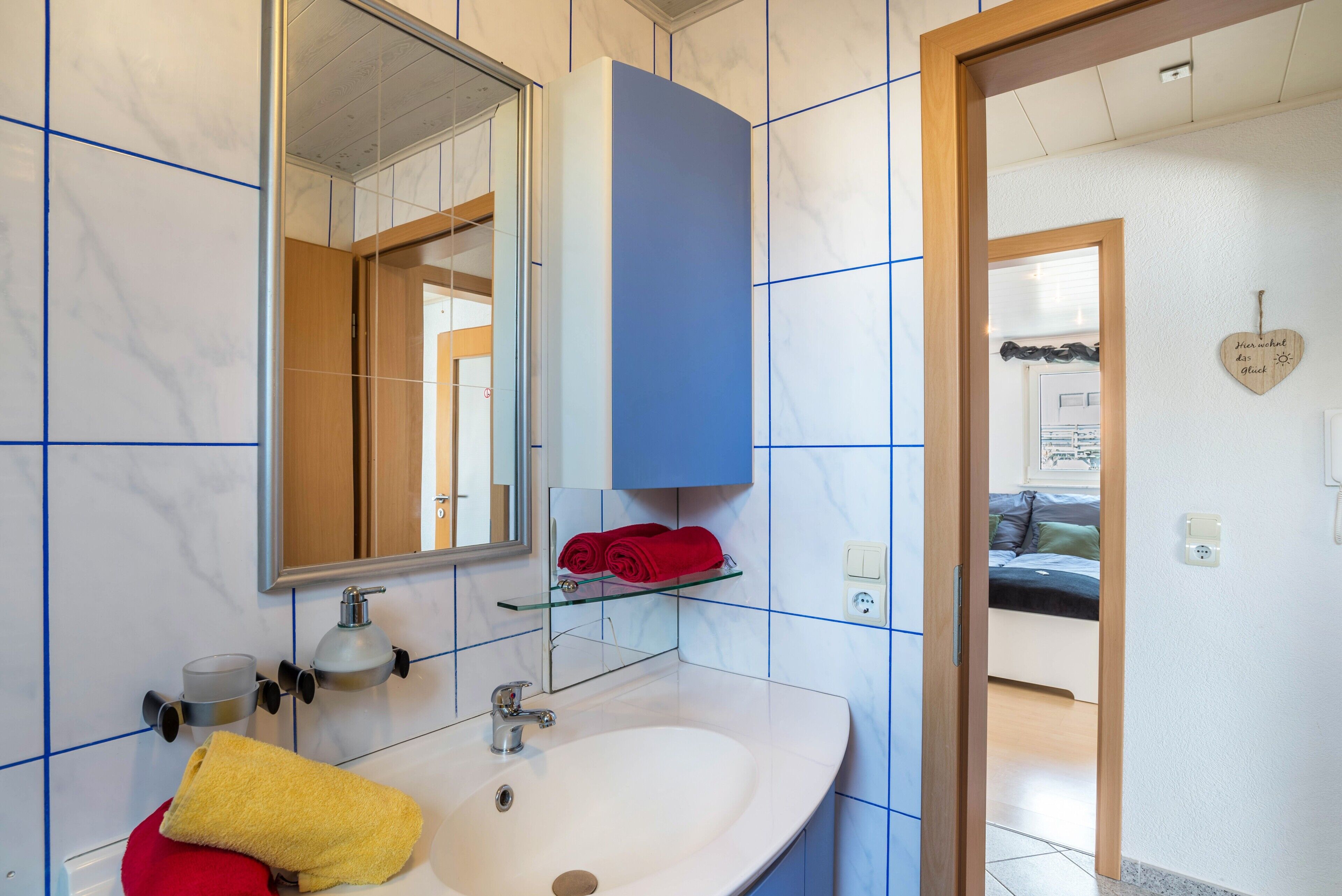 A bathroom with a white sink, mirror, and blue-tiled walls.