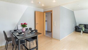 A dining area with a table set for four, a wooden door, and a living area with a couch. - Apartment 'Am Hirnach' with Shared Terrace, Shared Garden and Wi-Fi (Sindelfingen)