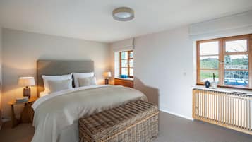 A bedroom with a bed, bedside lamps, a window, and a view of the outdoors.