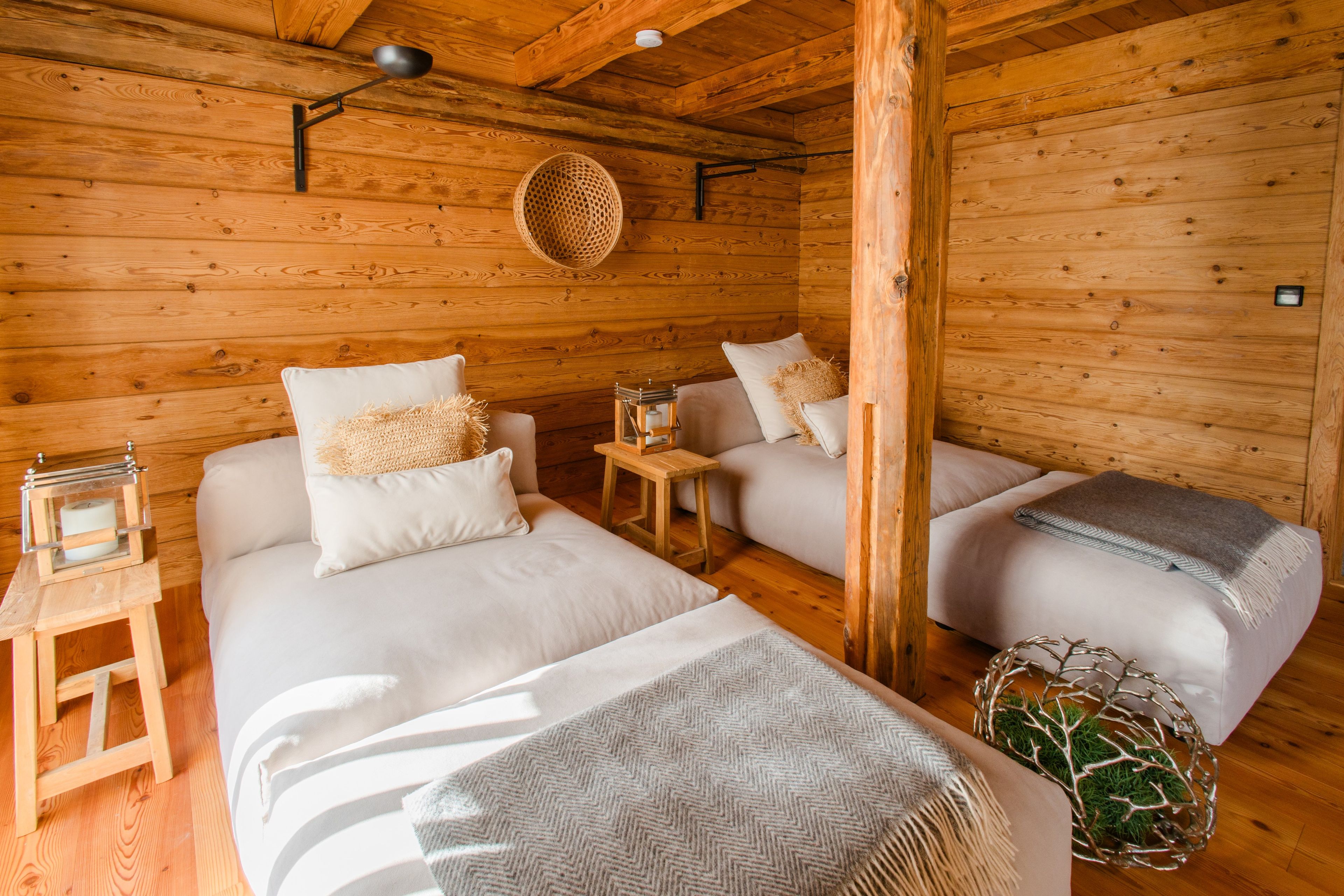 A cozy log cabin room with two beds, a small table, and a hanging basket.