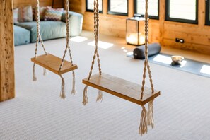 A room with a wooden swing suspended by ropes, a sofa, and a lamp in the background. - Chalet "Windhäusern 5" with Mountain View, Shared Garden & Wi-Fi (Wangen im Allgäu)