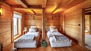 Una habitación tipo cabaña de madera con dos camas, una ventana y techo de madera.