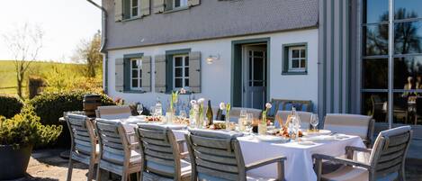 An outdoor dining area with a table set for four, surrounded by wooden chairs.