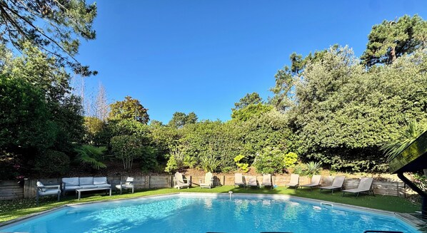 A swimming pool with lounge chairs and a wooden fence.