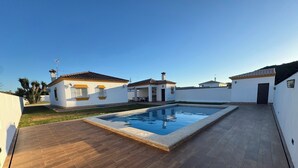 Ein Wohnhaus mit Schwimmbad, Holzterrasse und weißen Wänden.