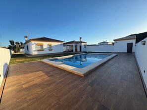A residential property with a swimming pool, wooden deck, and white walls. - Villa Orchard View in Chiclana (Chiclana)