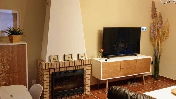 Ein Wohnzimmer mit Kamin, Fernseher und Essbereich.