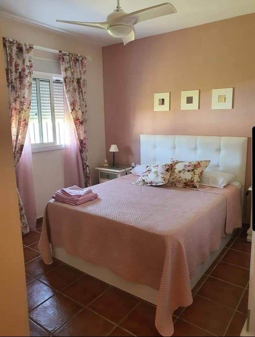 A bedroom with a bed, a nightstand, a lamp, and a ceiling fan.