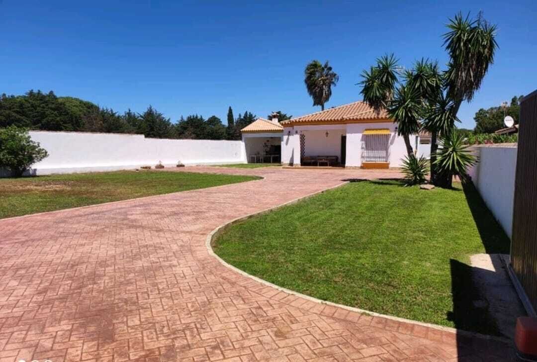Un camino pavimentado que conduce a una casa con techo de tejas y un pequeño porche.