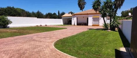 Un camino pavimentado que conduce a una casa con techo de tejas y un pequeño porche.