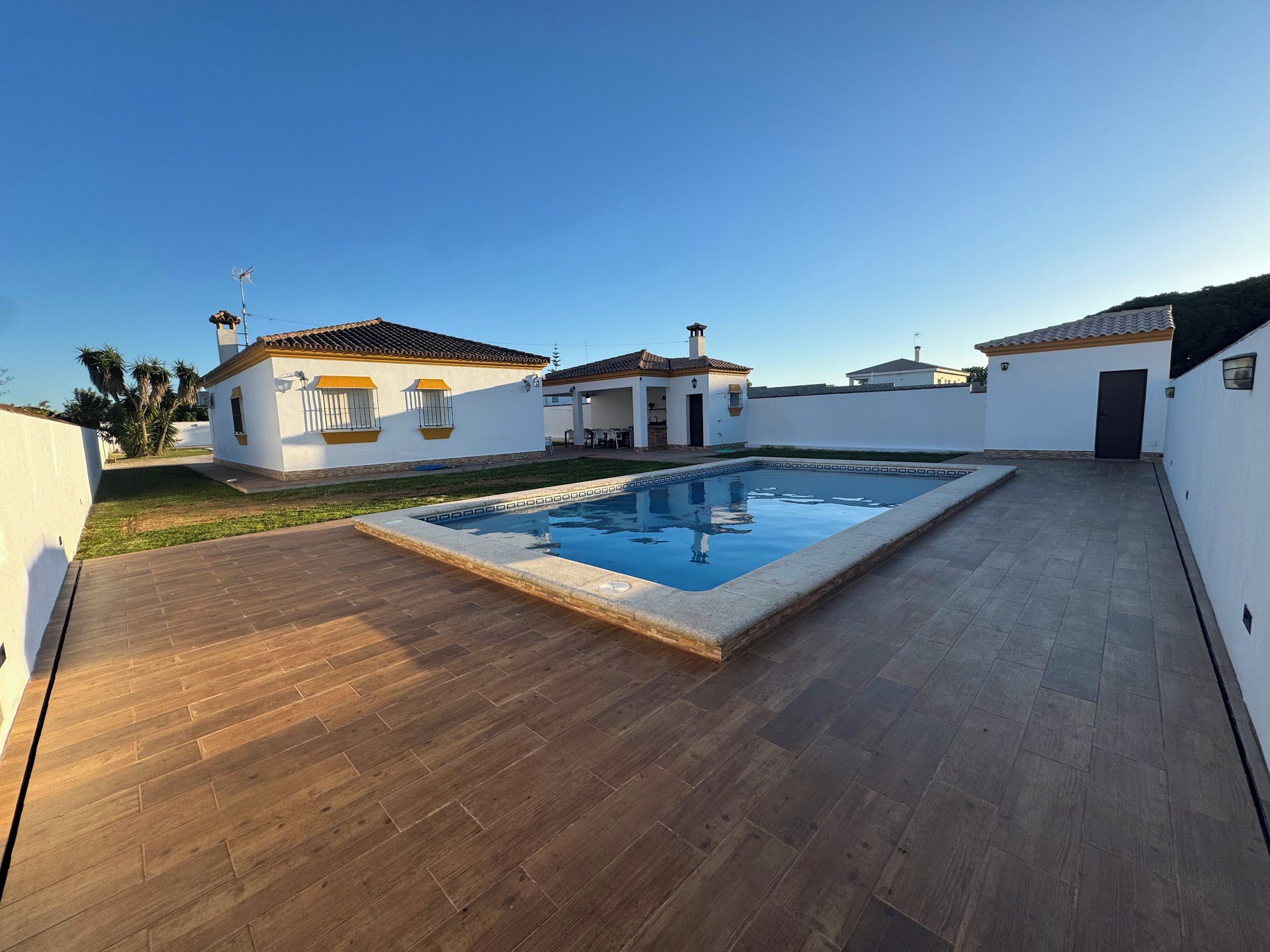 Ein Wohnhaus mit Schwimmbad, Holzterrasse und weißen Wänden.
