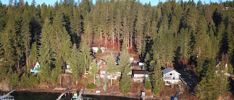 A lakeside property with docked boats, surrounded by dense forest.