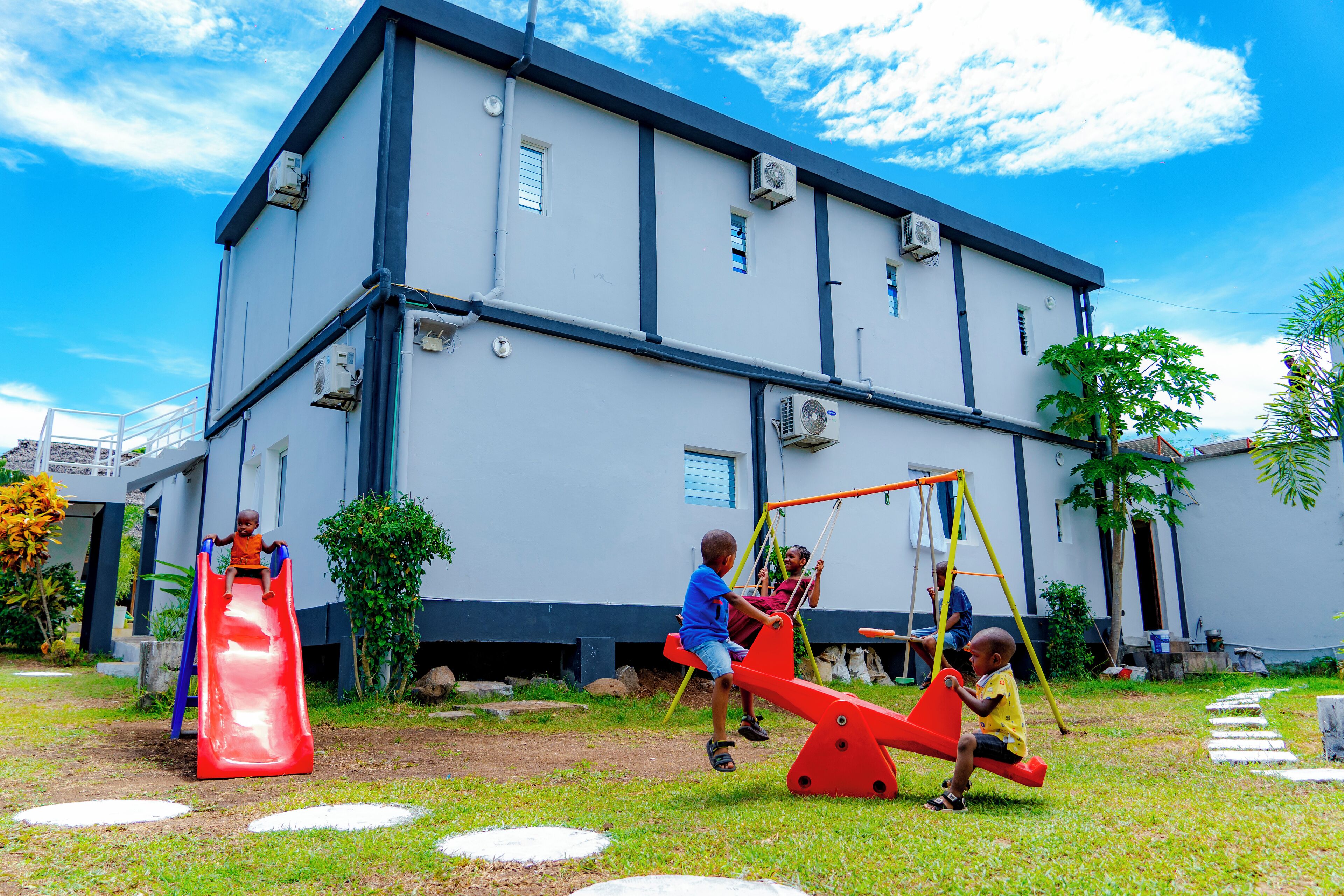 Children playing on a playground with a building in the background.