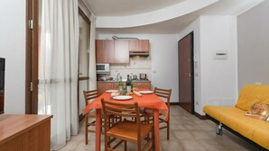 Un espace de vie compact comprenant un coin repas, une kitchenette et un canapé.