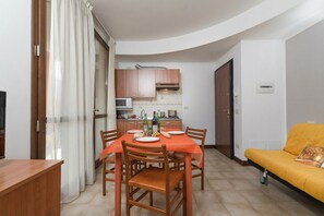 Un espacio habitable compacto con comedor, kitchenette y sofá.