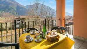 A balcony with a table set for two, a bottle, and a loaf of bread. - Porto Letizia Rossini 12, Porlezza, Italy (Porlezza)
