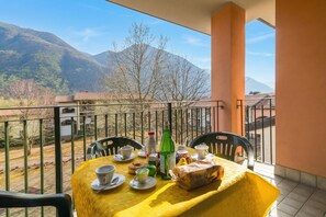 A balcony with a table set for two, a bottle, and a loaf of bread. - Porto Letizia Rossini 12, Porlezza, Italy (Porlezza)