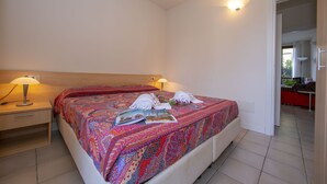 A neatly made bed with a colorful blanket, a bedside lamp, and a magazine on the bed. - Porto Letizia Roma 1, Porlezza, Italy (Porlezza)