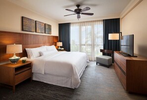 Relax in a stylish room with a large bed, flat-screen TV, and a view of lush greenery.