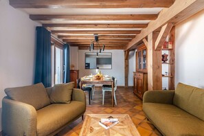 A living room with two sofas, a coffee table with a book, a dining table with chairs, and a kitchen area in the background.