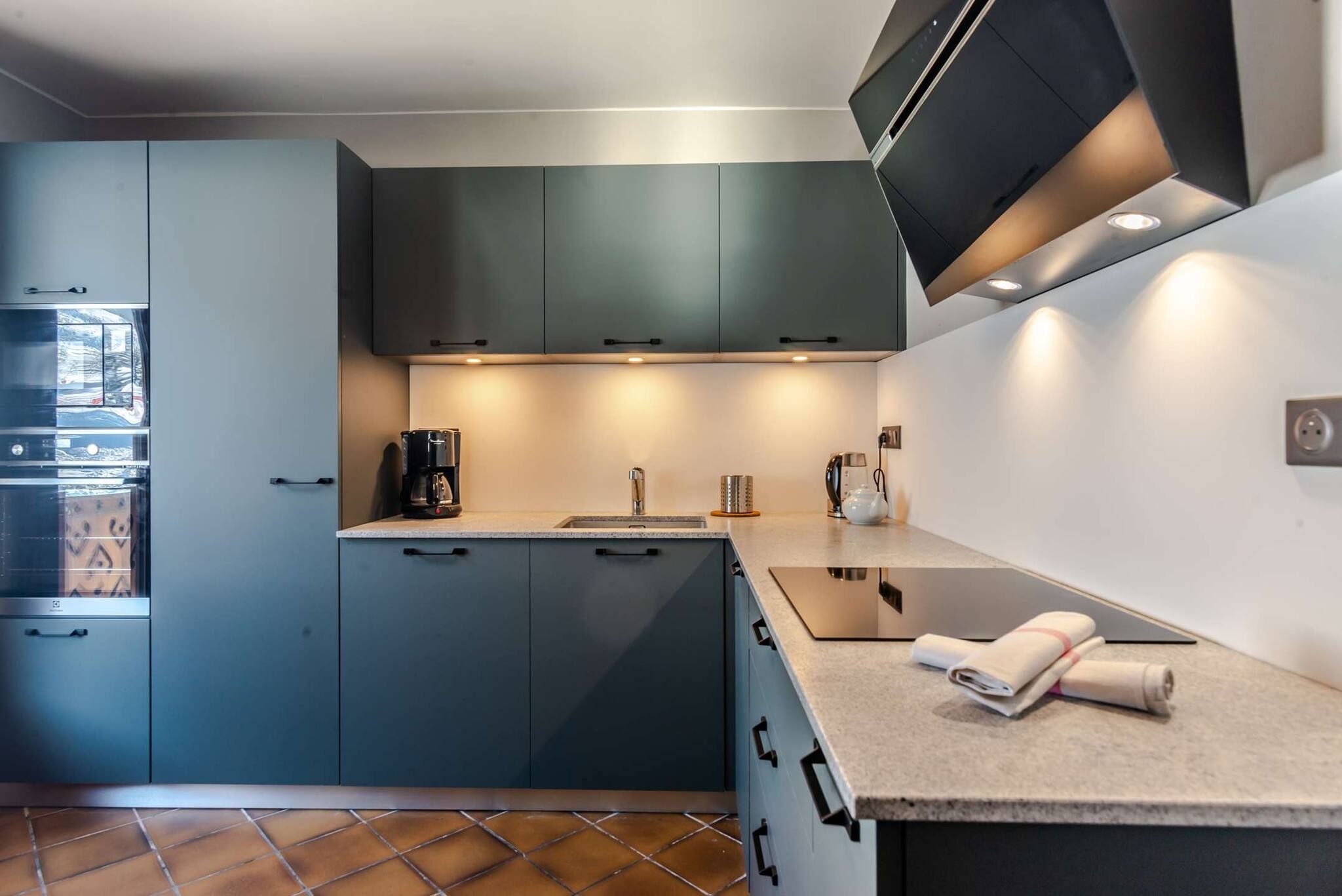 A modern kitchen with a built-in oven, a coffee machine, and a sink.