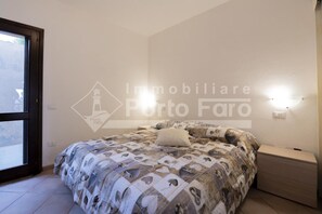 A bedroom with a bed, a nightstand, and a wall-mounted light fixture.
