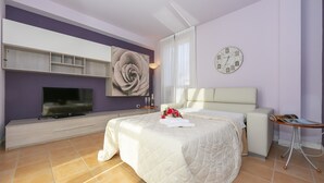 Un dormitorio moderno con una cama grande, un televisor, un reloj y una mesita.