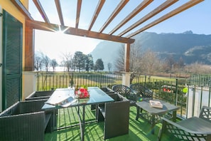 A covered outdoor area with a table and chairs, a pergola, and a view of mountains.