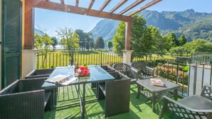 Un patio exterior con una mesa lista para dos personas, con vistas a un paisaje montañoso.