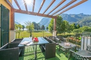 Une terrasse extérieure avec une table dressée pour deux personnes, offrant une vue sur un paysage montagneux.
